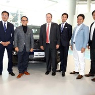 会場を訪れたトヨタ自動車社長 豊田章男氏とともに記念写真に収まる大使館公使カート・トン氏をはじめ出展社代表