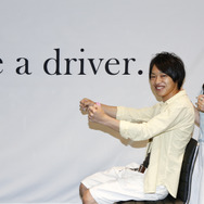会場に用意された「Be a driver」コーナーで記念撮影する20代カップルの参加者
