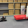 自律走行する先導ロボット「RoboCar 1/10」に追従するCarriRo、CarriRoのハンドルに搭載されたアンテナが周囲にある商品に貼付されたRFIDを読み取り、無人にて棚卸しを行う