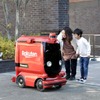 配送先にUGVが到着し、商品を受け取るユーザー