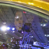 金色のクルマの運転席にはイーロン・マスクのマスク（お面）