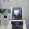 「フローティングビジョン」とFeliCaを連携させた提案。FeliCa対応の携帯電話を手前の台の上に置くと、「気球」の浮遊映像が携帯電話の中に飛び込むアニメーションが表示され、携帯電話にはURLなどの情報が取り込まれる
