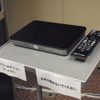 現在ぷららで開発中の専用チューナ「ST-4100」。今年12月下旬に提供される予定。従来の4Kテレビには、これを後づけで接続し、そこからLANケーブルを引き出してルータに接続する