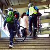 自転車を担いで階段を昇り、モノレール乗り場へと向かう参加者たち（11月30日、千葉モノレール実証実験「サイクル＆モノレール」）