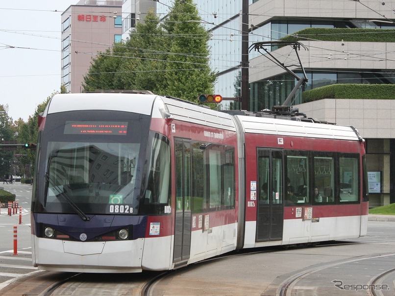 熊本市電の幹線（A系統）慶徳校前～辛島町を行く0800形超低床電車。「神水・市民病院前」はA系統（健軍町～熊本駅前・田崎橋）とB系統（健軍町～上熊本駅前）の停留場。「上熊本駅前」はB系統の停留場。